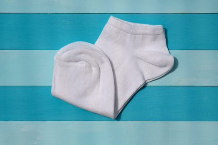 White cotton socks on a blue wooden background. White short socks for sports top view. New white...