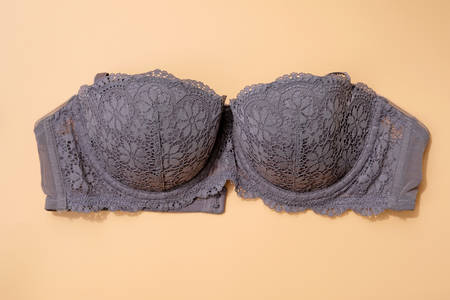 Gray lace bra on a beige background. Sexy bra with lace without straps  top view. Beautiful lingerie, a gift for beloved one.の写真素材