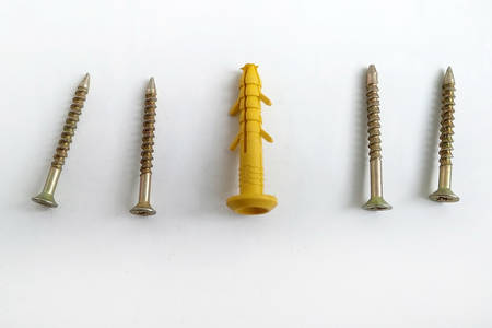 Yellow plastic dowels with metal screws on a white background. Construction material. An anchor is a fastener to hold any structure.の写真素材