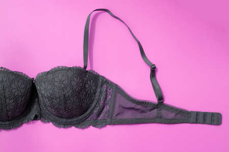 Gray bra on a pink background top view. Fragment of a lace bra with a fastener and straps. Beautiful sexy lingerie, concept of female sexuality, breast health.の写真素材