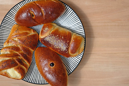 Tasty buns of different shapes on a plate top view. Homemade cakes with cottage cheese and berries....