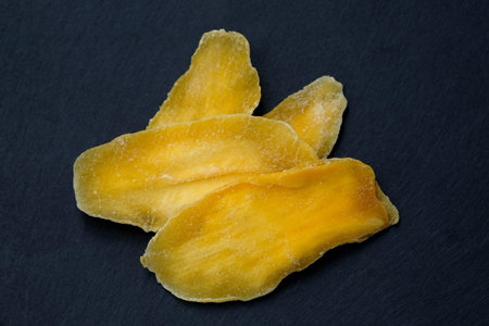 Dried mango without sugar. Natural mango petals on a black board top view. Dried mango pulp, dried...