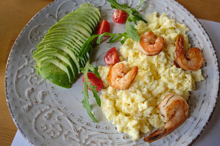 scrambled eggs with avocado and shrimps. delicious and healthy breakfast with avocado and seafood.の写真素材
