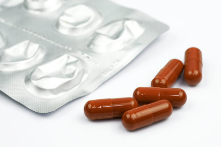 Brown capsules and blister on a white background. Liver protection tablets. Medical pills close up.