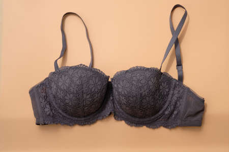 Gray lace bra with straps on a beige background. Push-up bra top view. Women's beautiful lingerie.の写真素材