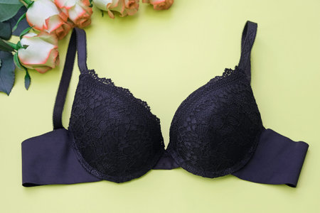 Black bra on a green background top view. Womens lace lingerie. Black bra with push-up cups and smooth shoulder straps on background of green color.