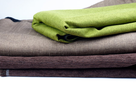 Folded pieces of fabric on a white background. Green and brown fabric for upholstery. Convolutions of fabric stacked on top of each other.の写真素材