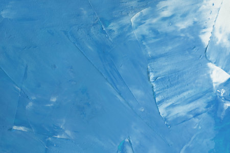 The surface is covered with blue paint with white streaks background. texture of paint on canvas....