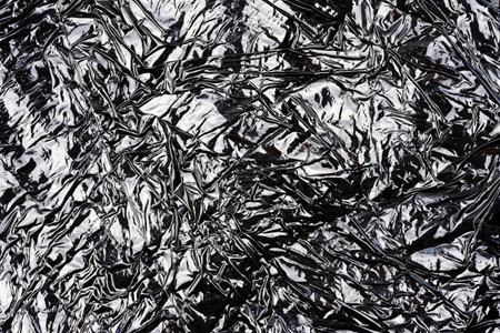 Black texture of packaging polyethylene top view. Abstract background of black color with highlights. Crumpled plastic bag close-up.の写真素材