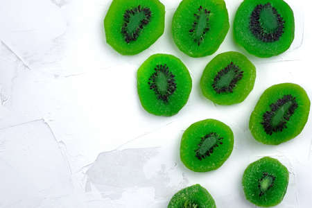 Candied kiwi fruits are laid out on a white background top view. Dried kiwi slices in sugar syrup.の写真素材