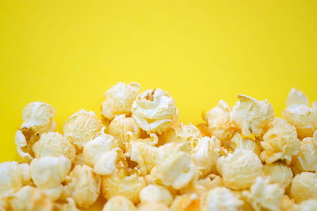Salted popcorn with cheese flavor on a yellow background top view. Corn grains from Argentina that are popping open. Large grains of popcorn with place for text.の写真素材