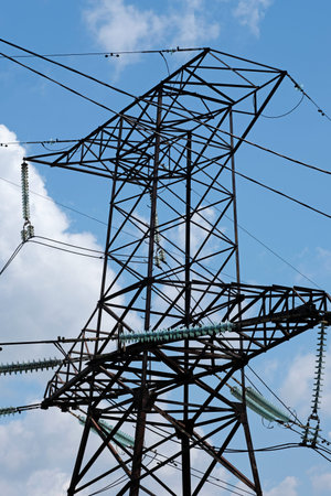 high voltage tower against blue sky bottom view. Power line. Transmission tower close-up. Metallic...
