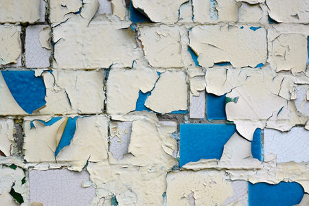 The brick wall is blue and beige. Painted wall with old peeling paint close-up. The background of...