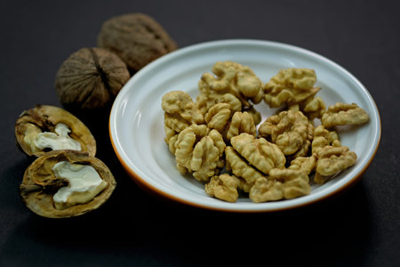 Young grains of walnut top view. Walnuts peeled and in shell on a black background. brown nuts,...