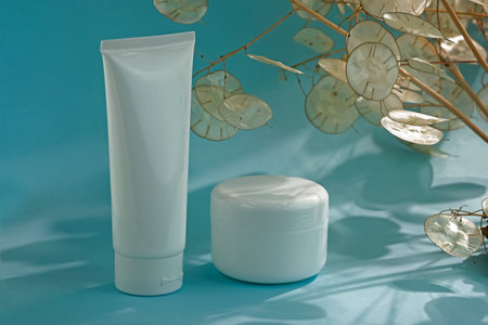 White plastic containers for cream on a blue background. Natural cosmetics concept. Empty white tube...