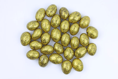 Almonds in chocolate and gold icing. Dragee in gold icing. Chocolate candy on a white background top...
