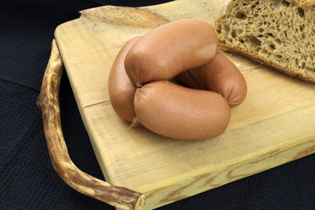 small sausage on a cutting board close-up. Sausages with bread. Pork sausages in a natural casing....