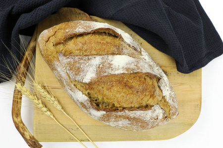 Rye bread sprinkled with flour top view. A loaf of bread with a toasted crust on a cutting board....