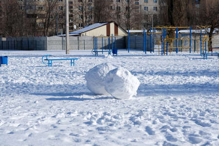 Two balls of snow on the playground in the yard. Sunny day in winter in a residential area of the city. snowman balls.の写真素材