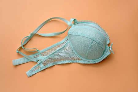 Green bra with lace on a beige background. Bra pale blue with pushap folded in two. Beautiful lingerie.の写真素材