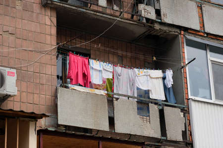 Laundry on the clothesline is dried on the old broken balcony. The balcony of a multi-story residential building. Poor areas of the city requiring home repairs.の写真素材