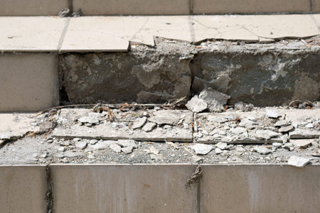 Steps with broken tiles on top. The tiles fell off the stairs. The old poor quality tile masonry at...