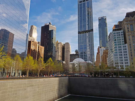 Mirrored skyscrapers and houses of old construction in the center of New York. Tourists near the 911 Memorial Fountainのeditorial素材