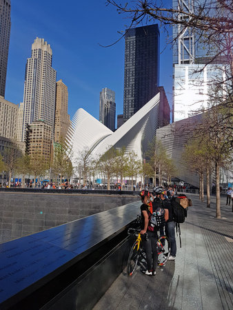 Memorial to the victims of 911 waterfall and the white Oculus building with groups of tourists....