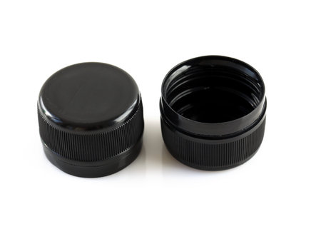 Two new black plastic caps on a white background. High dense plastic caps for plastic bottles. Circle screw lid for drink containers. Waste recycling concept.の写真素材