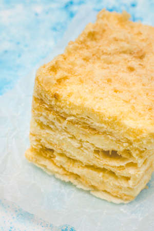 Slice of puff cake napoleon. Tasty cake on blue grunge backgroundの写真素材