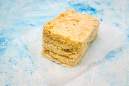 Slice of puff cake napoleon. Tasty cake on blue grunge background