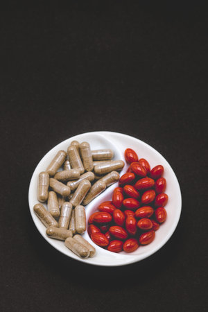Red pills and vegetarian pills on a plate. Two types of pills on a black background