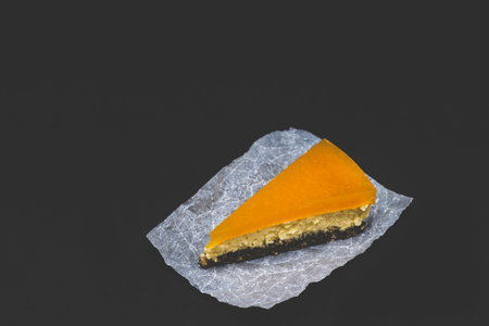 Piece of cheesecake with sea buckthorn and cake. Black background.