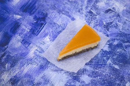 Piece of cheesecake with sea buckthorn and cake. Dark blue ink grunge backgroundの写真素材