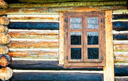 Dirty window of an old log cabin with different colored beams.の写真素材