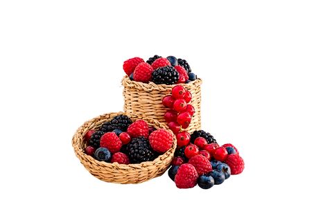 Raspberries,blackberries,blueberries and red currants in and around a wicker basket with lid isolated on white.の写真素材