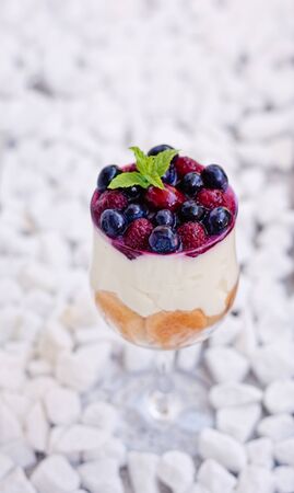 Forest fruits tiramisu with ladyfingers, vanilla seeds mascarpone and berries in a tall glass.の写真素材