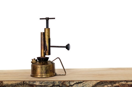 Old brass oil lamp on a wooden board agaist a white background.