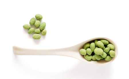 White porcelain spoon with wasabi coated peanuts isolated on whiteの写真素材