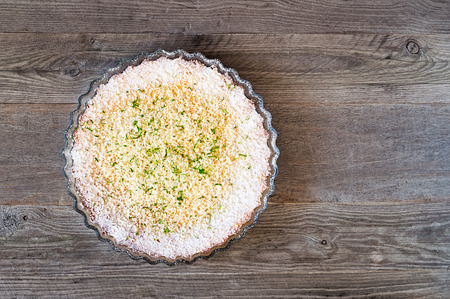 Lemon, lime, coconut impossible pie with white chocolate shavings on a weathered wooden tableの写真素材