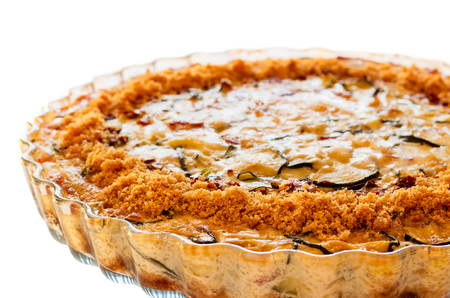 Close-up of homemade crustless zucchini quiche baked in a glass fluted dish isolated on whiteの写真素材