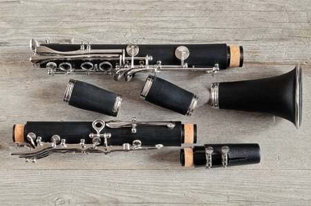 Top view of a black clarinet dismantled in four parts on a gray weathered wooden backgroundの写真素材