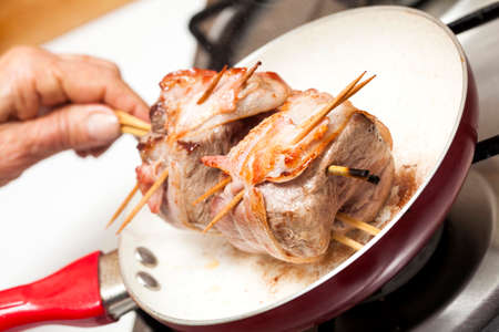 Browning the bacon wrapped around the beef tenderloin medallionsの写真素材