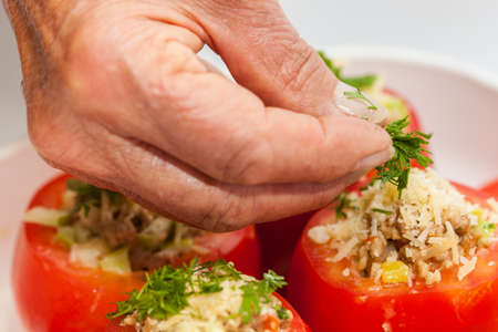 Stuffed tomatoes preparation : Adding coriander  to raw stuffed tomatoesの写真素材