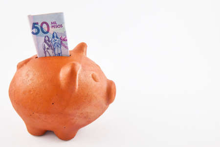 Saving Fifty Thousand Colombian Pesos Bills into a piggy bankの写真素材