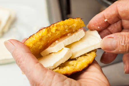 Traditional Colombian Arepa de Choclo Preparation: Stuffing the cooked corn bread with cheeseの写真素材