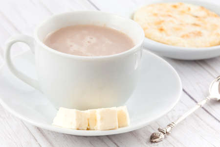 Cup of hot chocolate with cheese and arepa served in white dishwareの写真素材