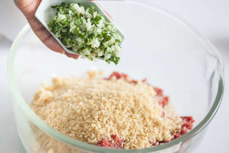 Step by step Levantine cuisine kibbeh preparation : Adding the ingredients to prepare kibbeh into a bowlの写真素材