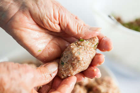 Step by step Levantine cuisine kibbeh preparation : Close up of a senior woman hands shaping a kibbehの写真素材