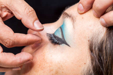 Close up of a makeup artist applying the false eyelashes to a womanの写真素材